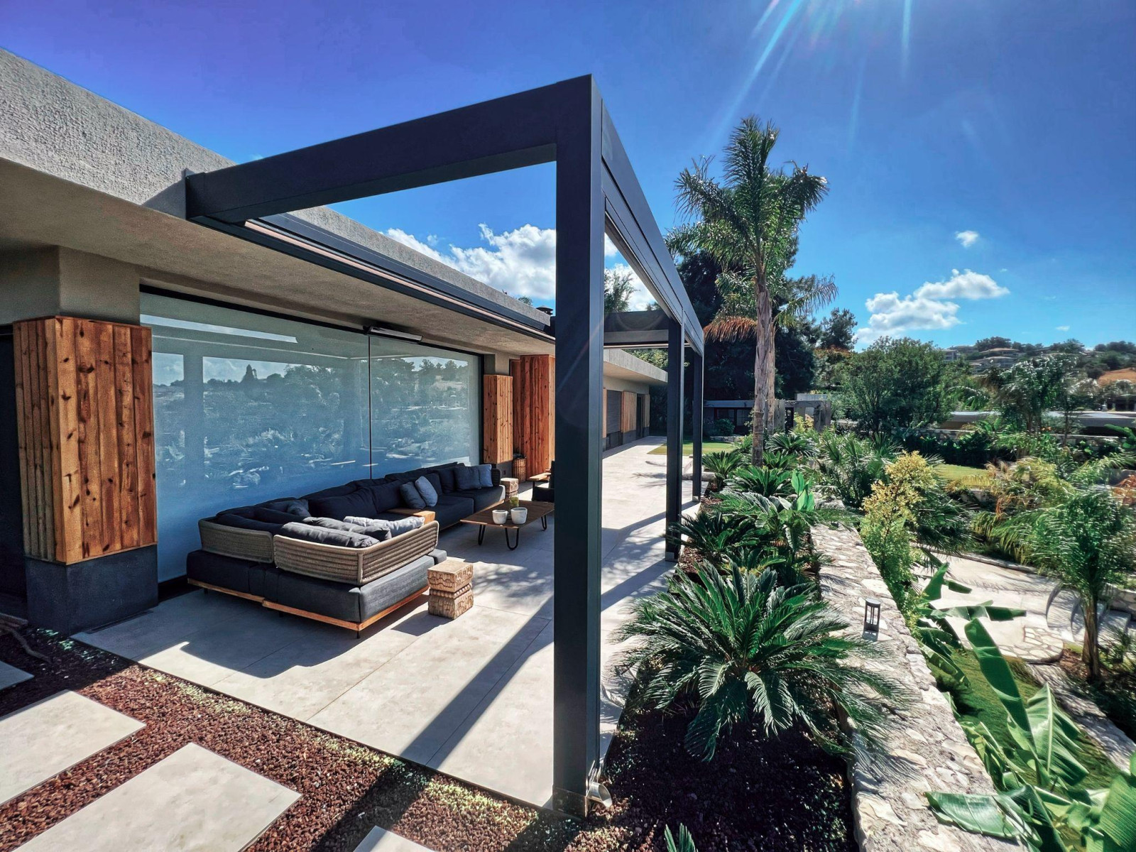 A stylish modern residence with a generous patio area, offering flexible modular seating arrangements under a pergola.