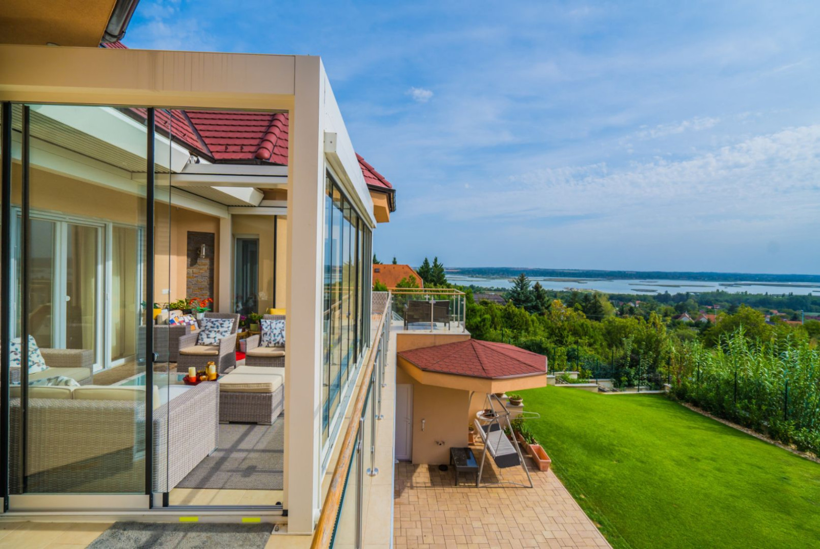 . A summer patio with a glass wall and a pergola, creating an inviting outdoor area for relaxation.