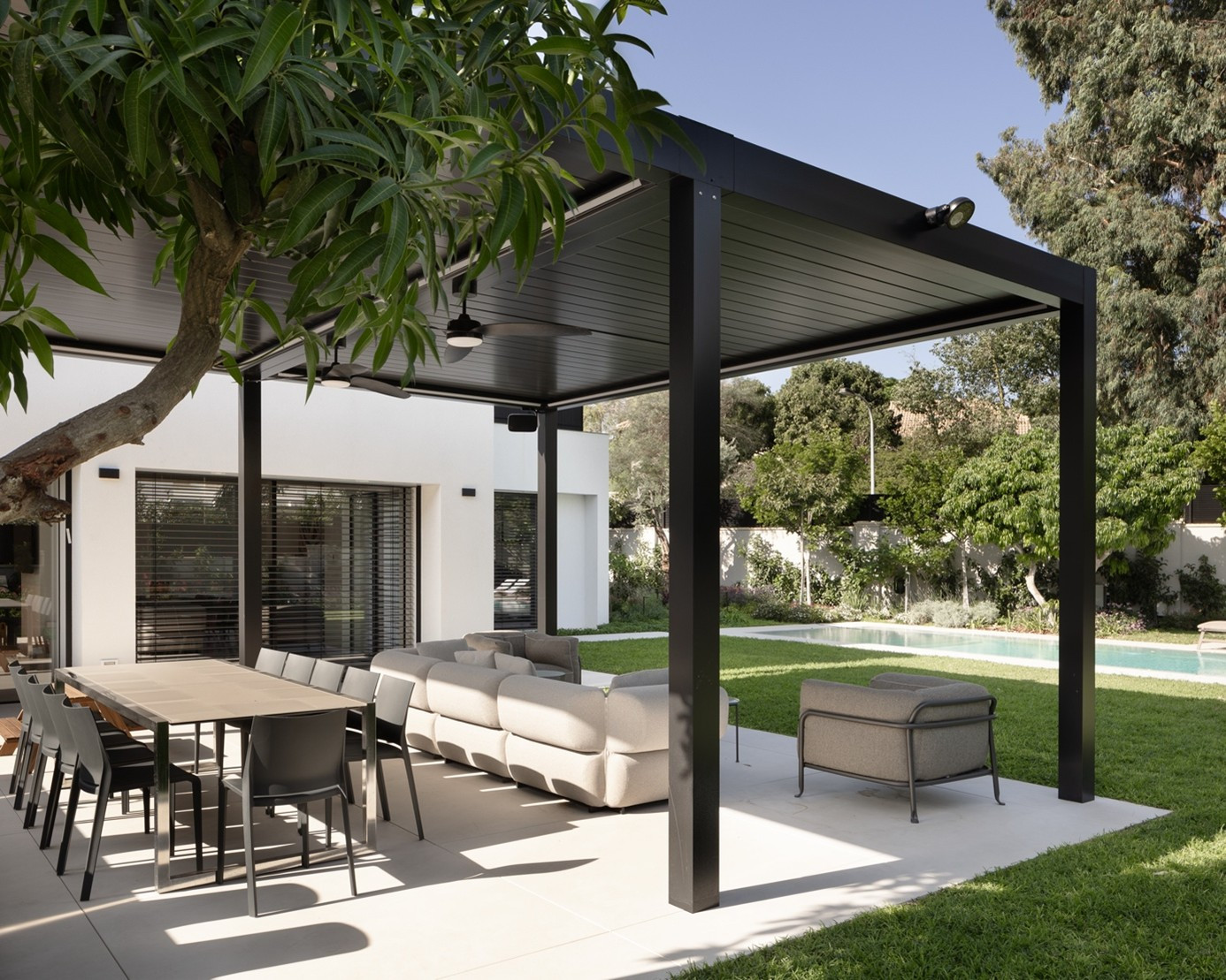 Black aluminium pergola system shading the dining and lounge area on a modern home terrace