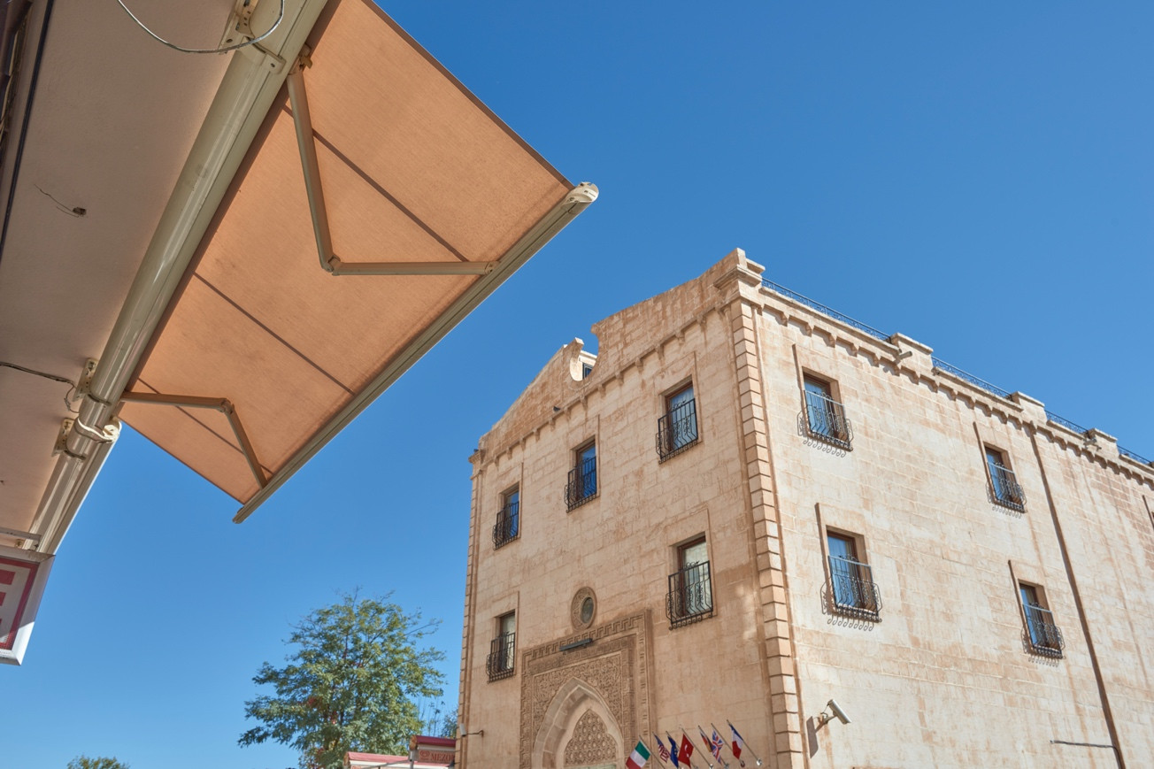 Fabric awning texture integrated with a natural stone exterior façade for architectural shading harmony